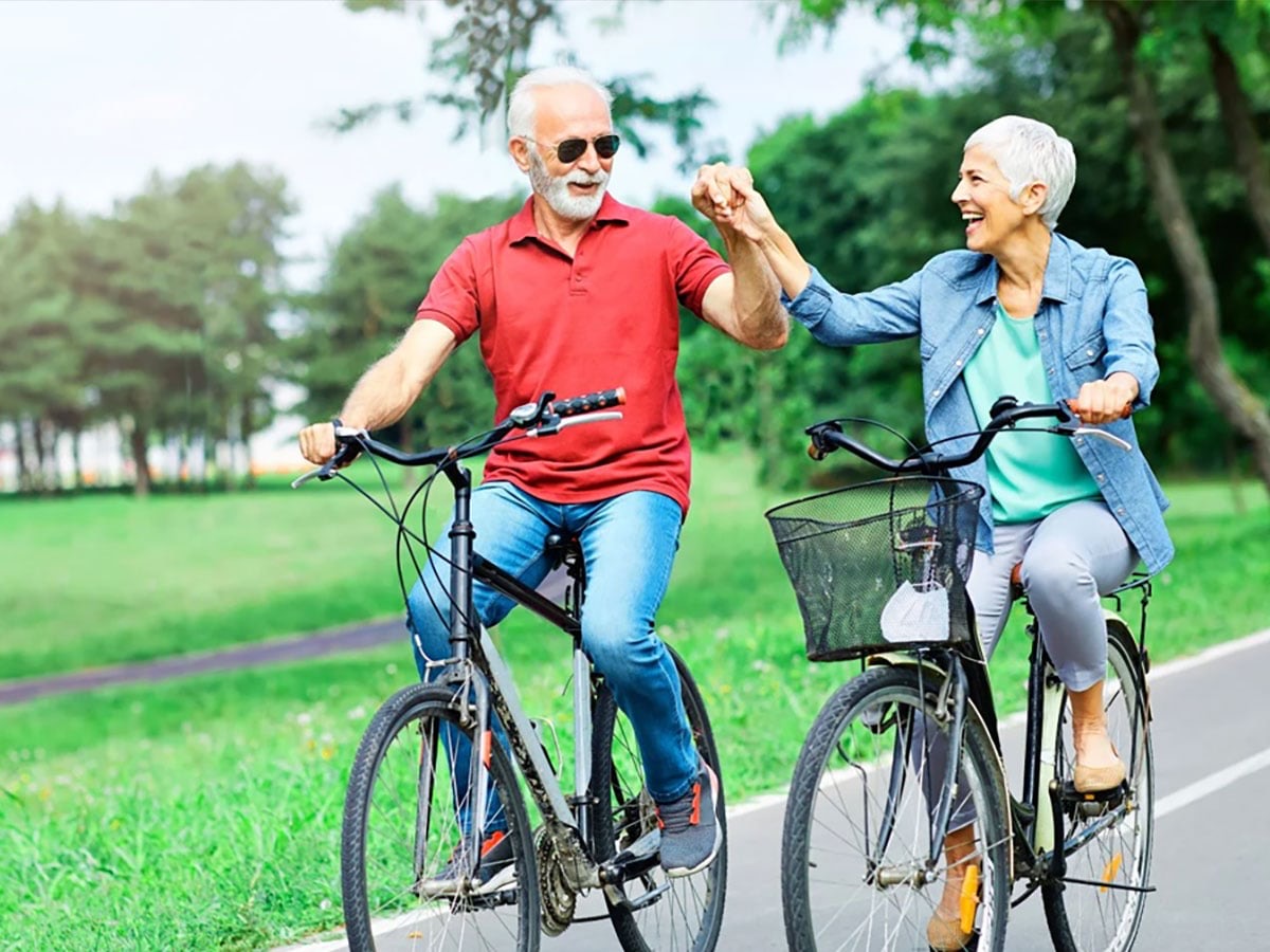 Pareja adulta paseando en bicicleta por el parque