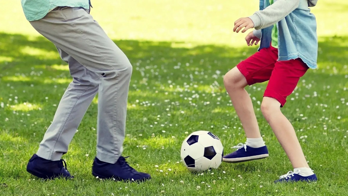 Abuelo jugando fútbol con su nieto en el pasto